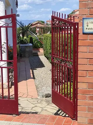 a red gate in front of a brick building at a18' de Barcelona y 10' de circuito de Cataluña in Barcelona