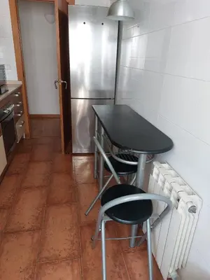 a table and two chairs in a kitchen with a refrigerator at Apartamento tranquilo cerca de la Sagrada Familia in Barcelona