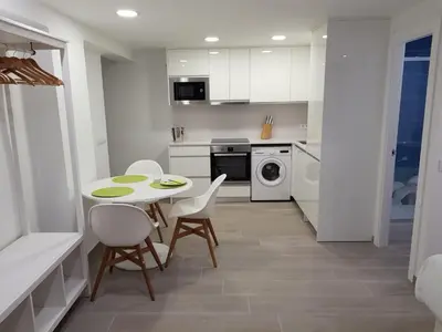 a white kitchen with a table and chairs in it at Eros Apartament in Calella