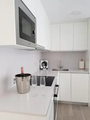 a white kitchen with two wine glasses and a microwave at Eros Apartament in Calella