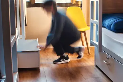 a person kneeling on the floor in a room with a yellow chair at Factory Hostels Barcelona in Barcelona