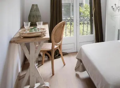 a wooden table with two chairs and a table with glasses at La Maison de Barcelone in Barcelona