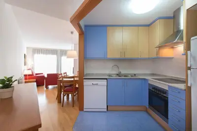 a kitchen with blue cabinets and a living room at Sweet Apartments in Sant Pere de Ribes
