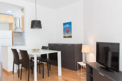 a dining room with a table and chairs and a television at Sweet Apartments in Sant Pere de Ribes