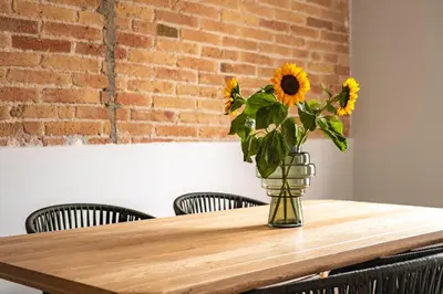 a vase of sunflowers sitting on a wooden table at Aspasios Garden Apartments in Barcelona