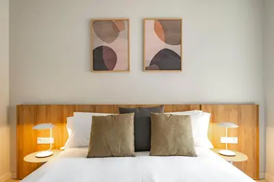 a bedroom with a large white bed with two lamps at Aspasios Garden Apartments in Barcelona