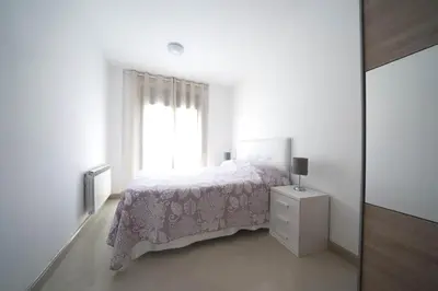 a white bedroom with a bed and a window at Apartamento centro histórico en Manresa in Manresa