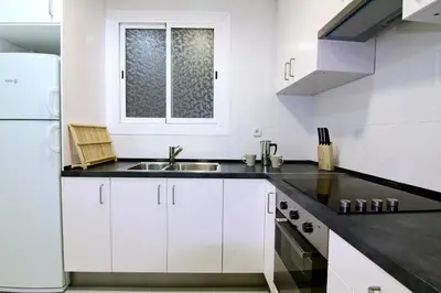 a kitchen with white cabinets and a sink at ClassBedroom Gaudí Apartments in Barcelona