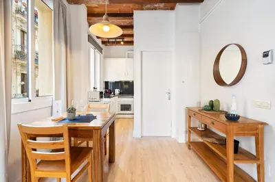 a kitchen with a wooden table and wooden chairs at Lodging Apartments Beach Studio 11 in Barcelona