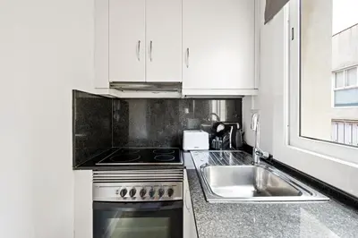a white kitchen with a sink and a stove at Lodging Apartments Beach Studio 22 in Barcelona