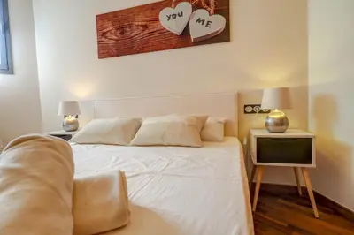 a bedroom with a white bed with two night stands and two lamps at Seaside April Apartment by Hello Homes Sitges in Sitges