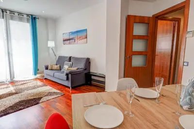 a living room with a table and a couch at Seaside April Apartment by Hello Homes Sitges in Sitges