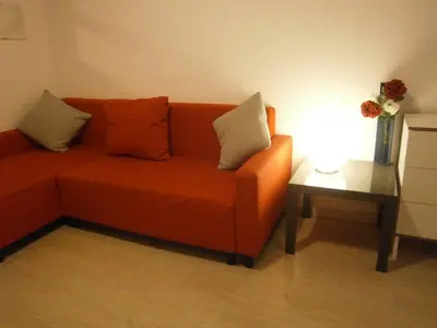 an orange couch with pillows next to a side table at Marbel Apartments in Barcelona