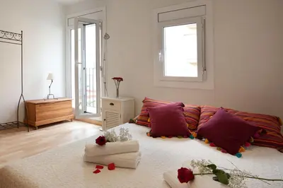 a room with a bed with purple pillows and roses on it at Homenfun Barcelona Montjuic in Barcelona
