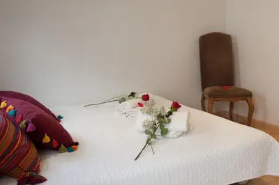 a white bed with a bouquet of flowers on it at Homenfun Barcelona Montjuic in Barcelona