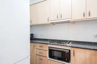 a kitchen with wooden cabinets and a microwave at Homenfun Barcelona Gracia in Barcelona