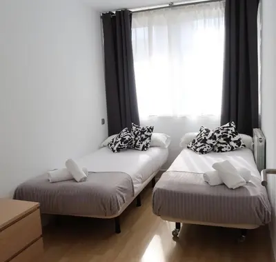 two beds in a room with a window at Apartments BCN Central-Montjuic in Barcelona
