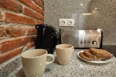 a counter with two cups and a toaster and a slice of bread at BBarcelona Sagrada Familia Flats in Barcelona