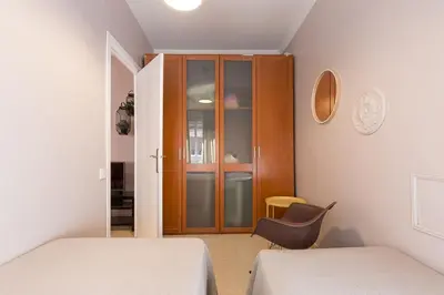 a bedroom with two beds and a cabinet and a chair at ApartEasy - Plaza España & Fira in Barcelona