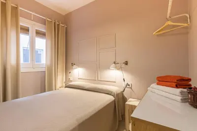 a bedroom with two beds and a sink and a window at ApartEasy - Plaza España & Fira in Barcelona