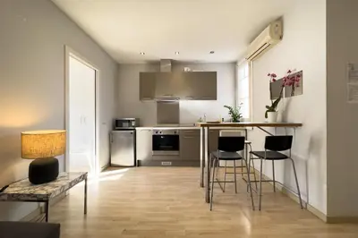 a kitchen with a bar with chairs and a table at ApartEasy - Gracia Apartments in Barcelona