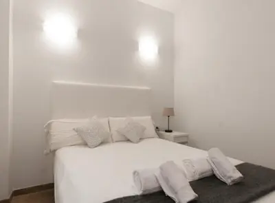 a white bedroom with a white bed with pillows at Picasso Suites in Barcelona