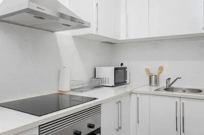 a white kitchen with a sink and a microwave at Bright 3bdr Near To The Metro in Hospitalet de Llobregat