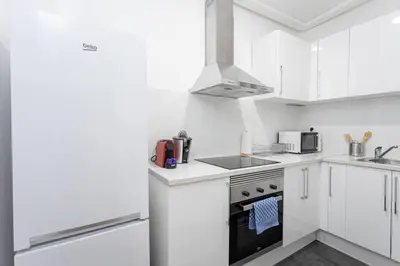 a white kitchen with a stove and a microwave at Bright 3bdr Near To The Metro in Hospitalet de Llobregat