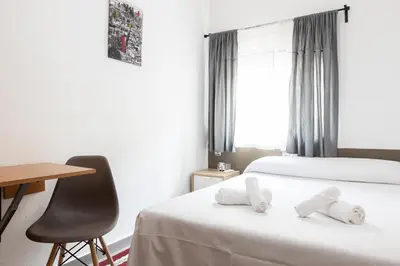 a bedroom with a bed and a desk and a chair at Pensión Galicia in Canovellas