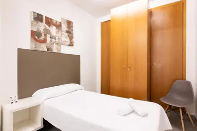a bedroom with a white bed and a wooden cabinet at Pensión Galicia in Canovellas