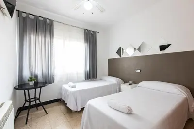 a hotel room with two beds and a window at Pensión Galicia in Canovellas