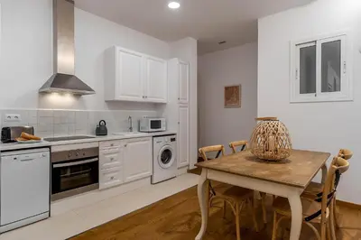 a kitchen with white cabinets and a table with chairs at AB Eixample Calabria in Barcelona