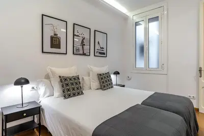 a white bedroom with a large bed and a window at AB Eixample Calabria in Barcelona