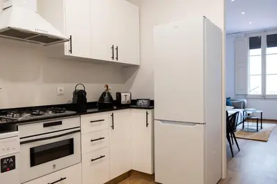 a kitchen with white cabinets and a white refrigerator at AB Eixample Calabria in Barcelona