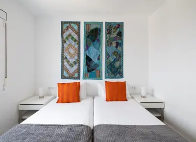 two beds in a room with white walls and orange pillows at Stay U-nique Apartments Taulat in Barcelona