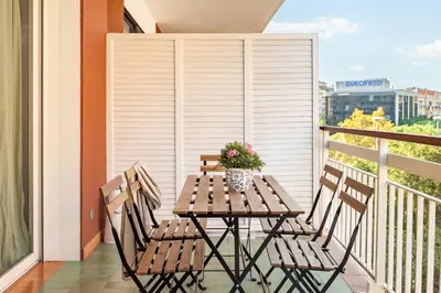 a wooden table on a balcony with two chairs at Flateli Paris in Barcelona