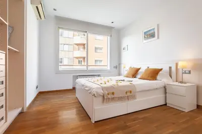 a white bedroom with a white bed and a window at Flateli Paris in Barcelona