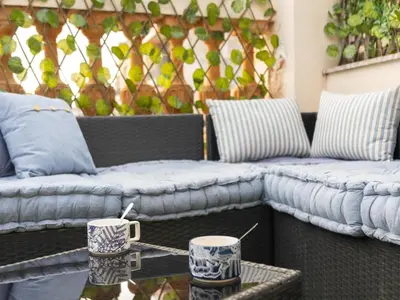 a patio with a couch and two mugs on a table at Matarolux23 in Mataró