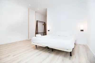a white bed in a room with a wooden floor at Cathedral Apartments in Barcelona