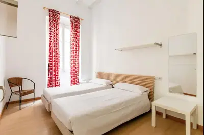 a bedroom with two beds and a chair and a window at BELLAFILA GOTHIC in Barcelona