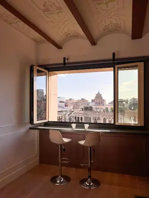 a bar with two stools in front of a large window at Passeig de Gràcia by Enjoybcn in Barcelona