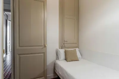 a bedroom with a white bed and a door at AB Bailen Apartments in Barcelona