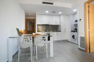 a kitchen with white cabinets and a table and chairs at BBarcelona Gaudí Flats in Barcelona