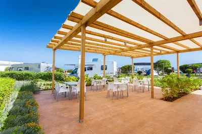 a wooden pergola with tables and chairs on a patio at Tres Estrellas Barcelona by HolaCamp in Gavà