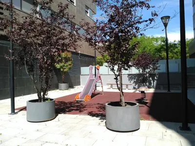 two trees in pots with a slide in a courtyard at 2 BEDROOMS and 2 BATHROOMS FOR 5 PAX, SWIMMING POOL, FREE PARKING and NEAR THE BEACH! in Sant Adria de Besos