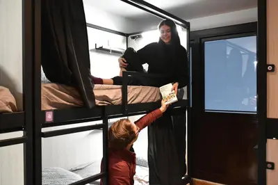 a young child is reaching for a man in a bunk bed at Onefam Batlló in Barcelona