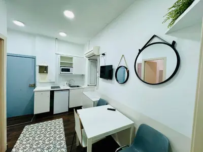 a small white kitchen with a mirror and a table at 028 Apartament 2 2 in Barcelona