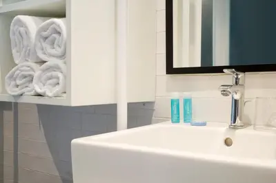 a white bathroom with a sink and towels at Praktik Bakery in Barcelona