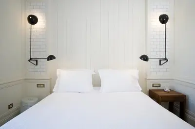 a white bed with two white pillows and two lights at Praktik Bakery in Barcelona