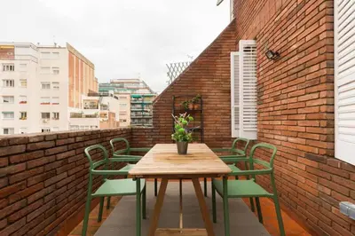a table and chairs on a balcony with a brick wall at 2 Bdr Penthouse In Grcia in Barcelona